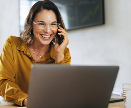 Woman speaking on her mobile while looking at her laptop